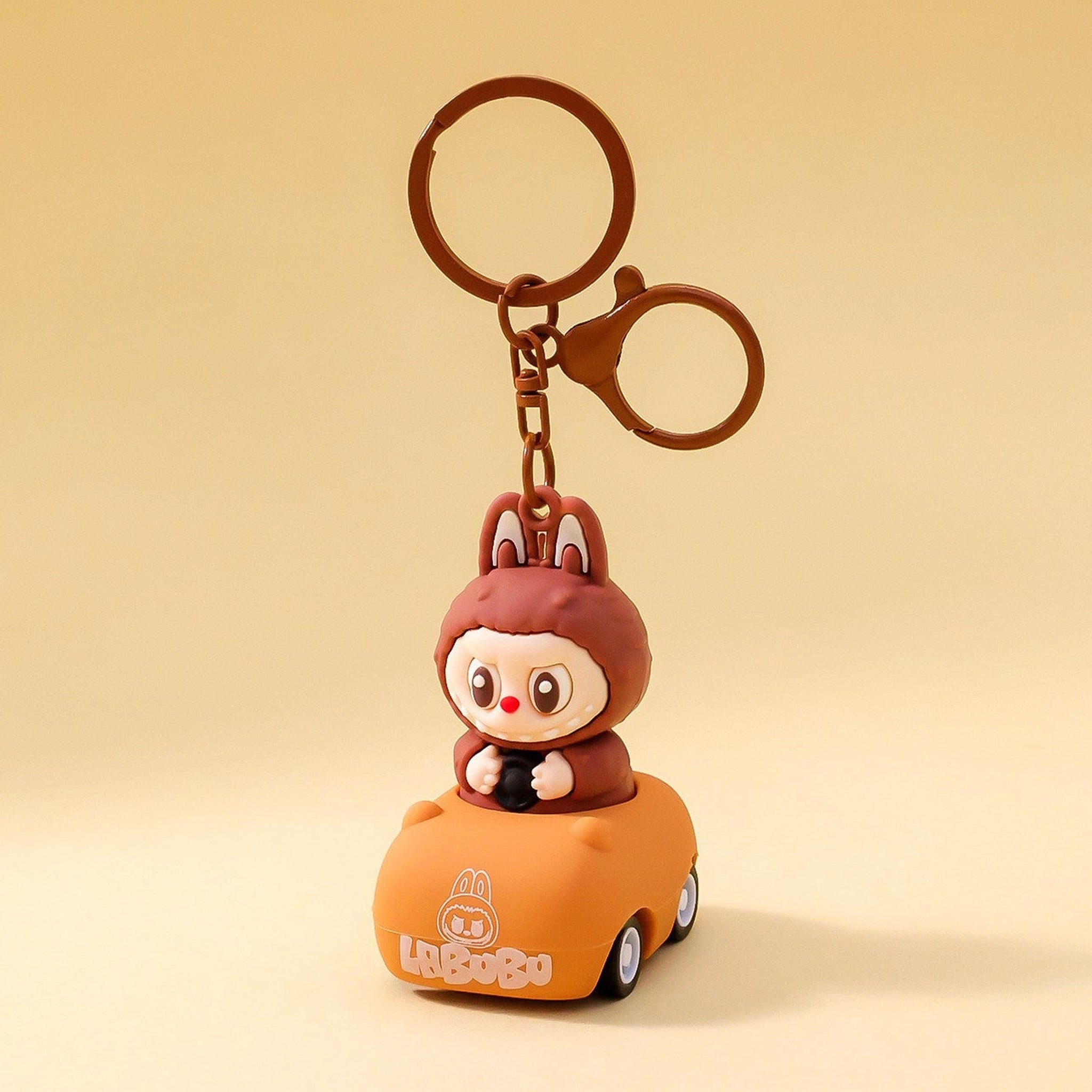 A brown labubu in a car shaped keychain. 