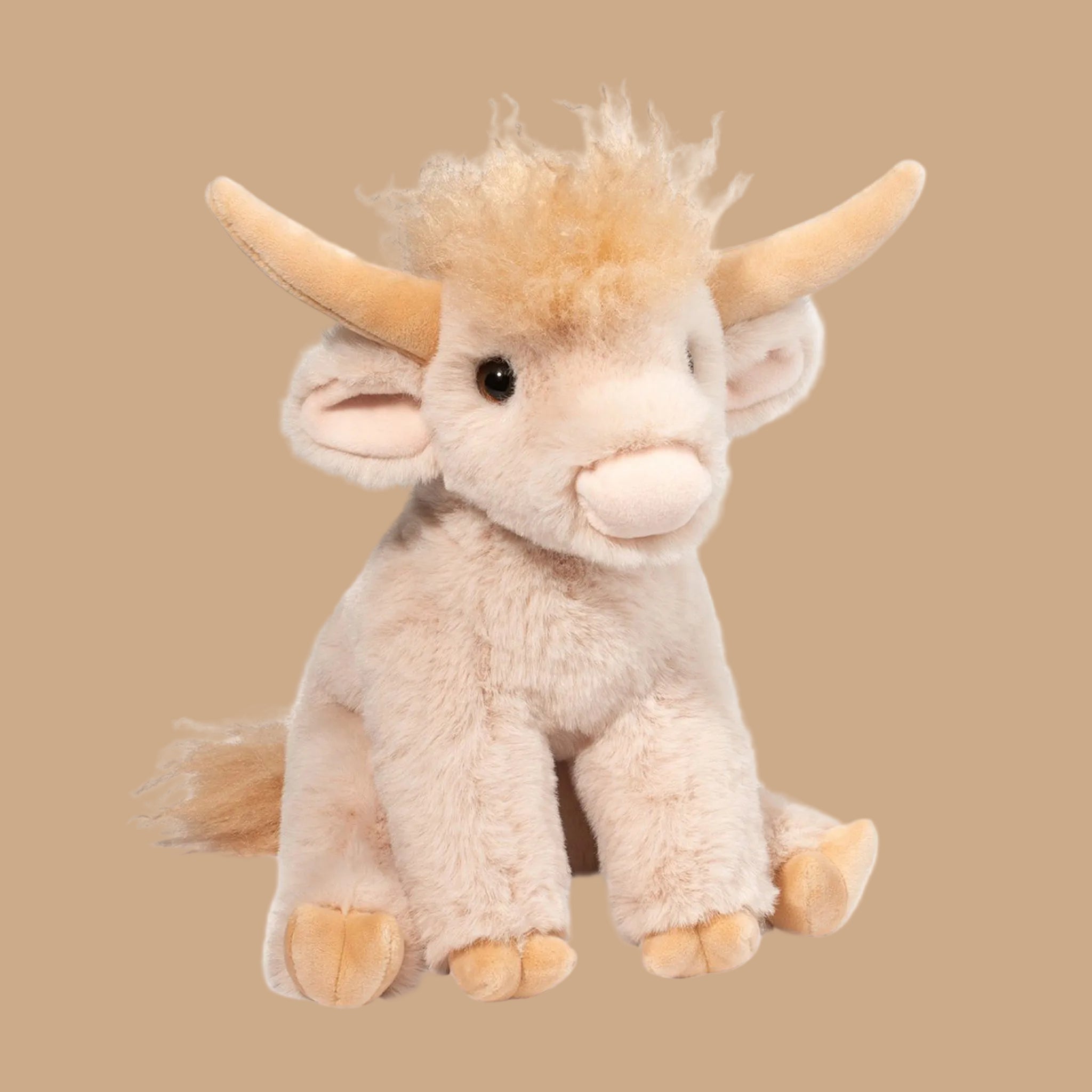 On a tan background is a tan highland cow shaped stuffed animal. 