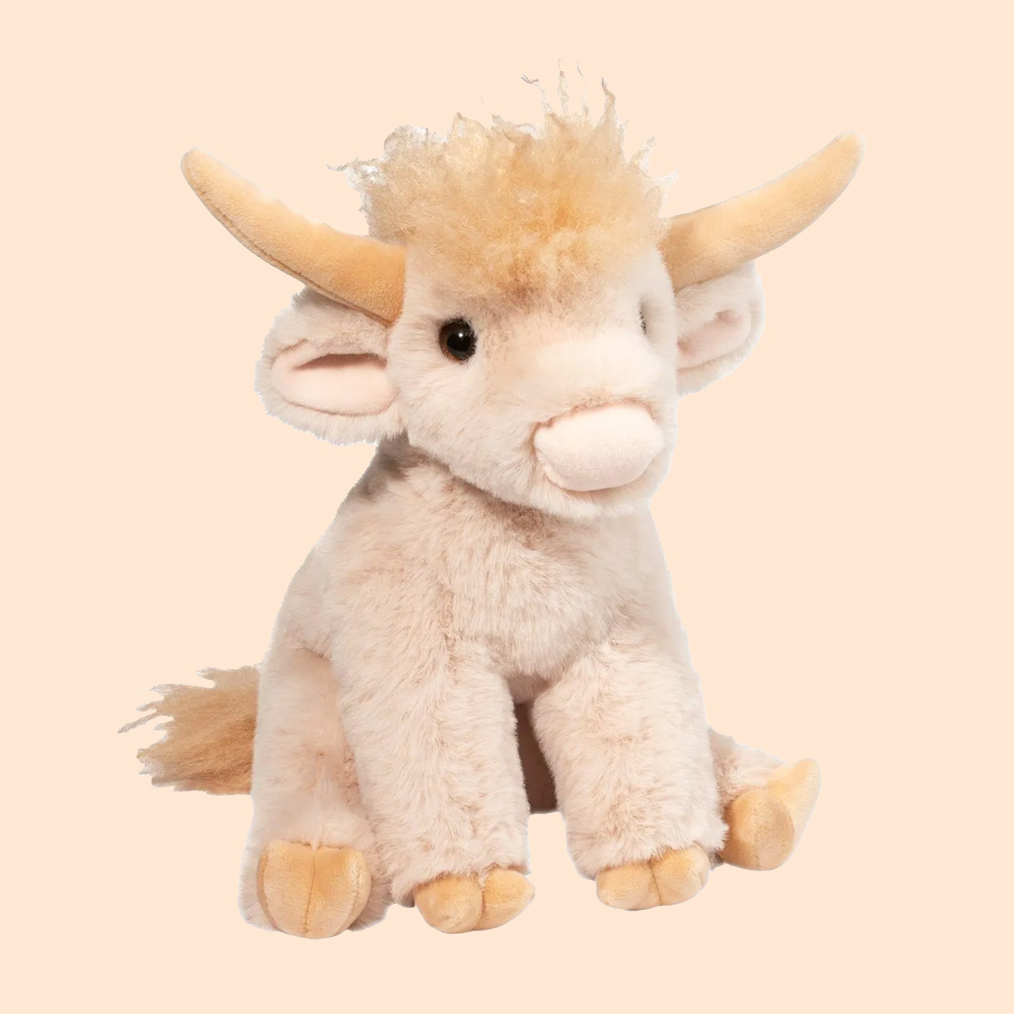 On a tan background is a tan highland cow shaped stuffed animal. 