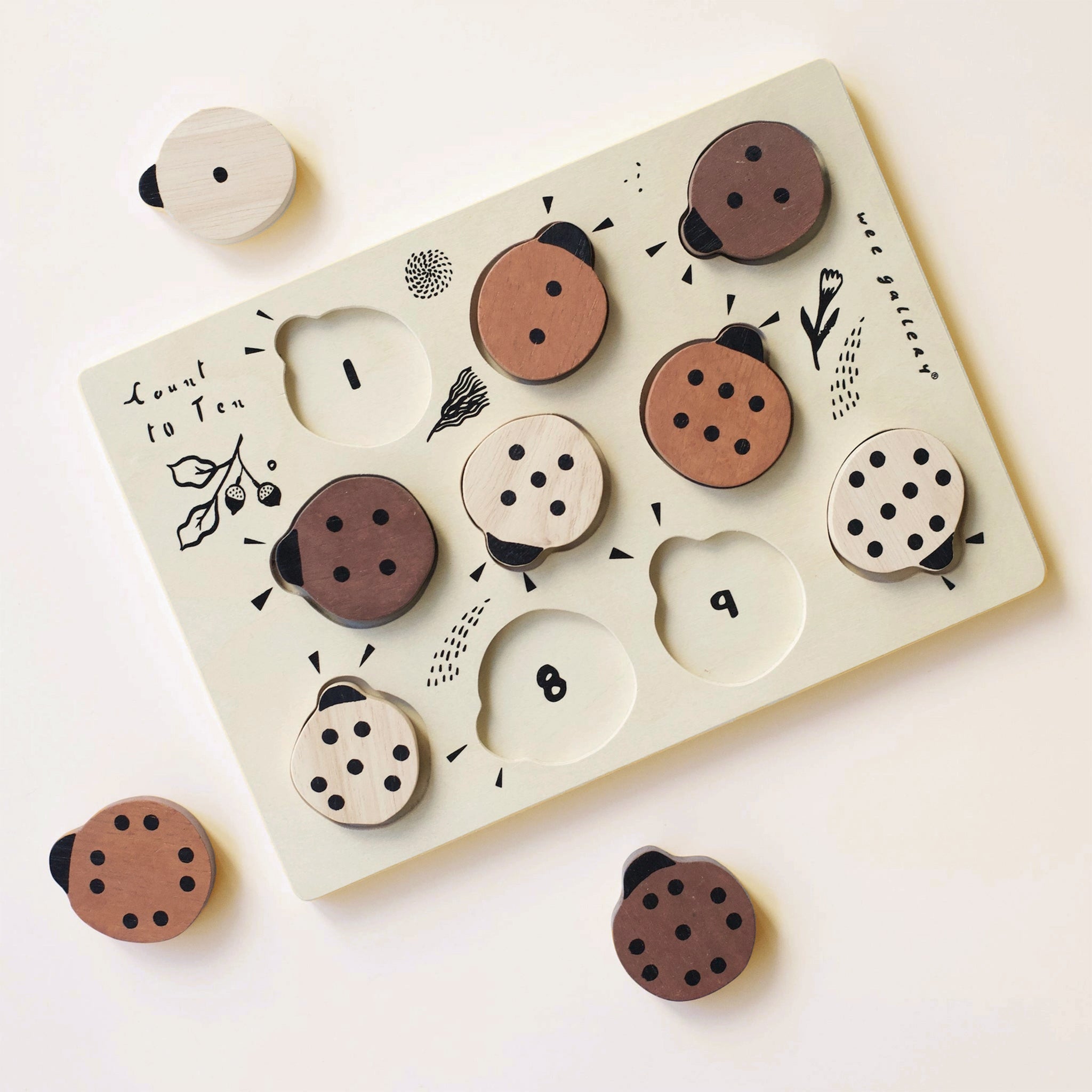 A wooden puzzle with ladybug shapes and numbers underneath. 
