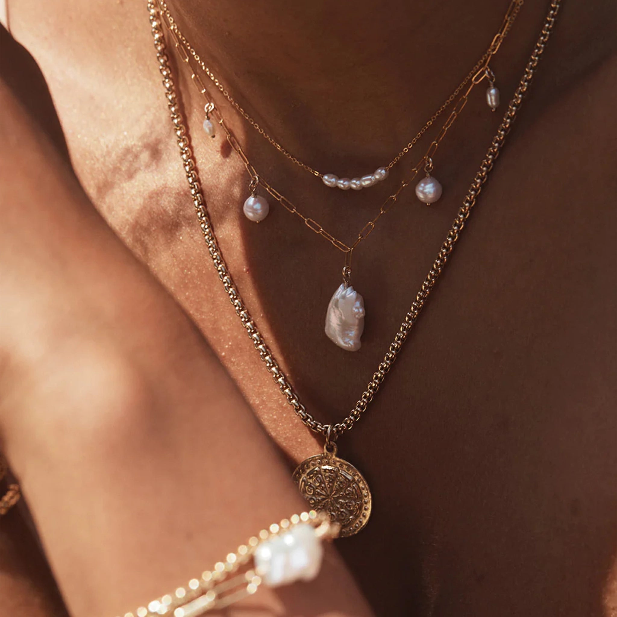 The dainty gold chain necklace with five small pearls lined next to each other. 