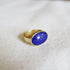 A gold chunky band ring with an oval lapis stone in the center. 