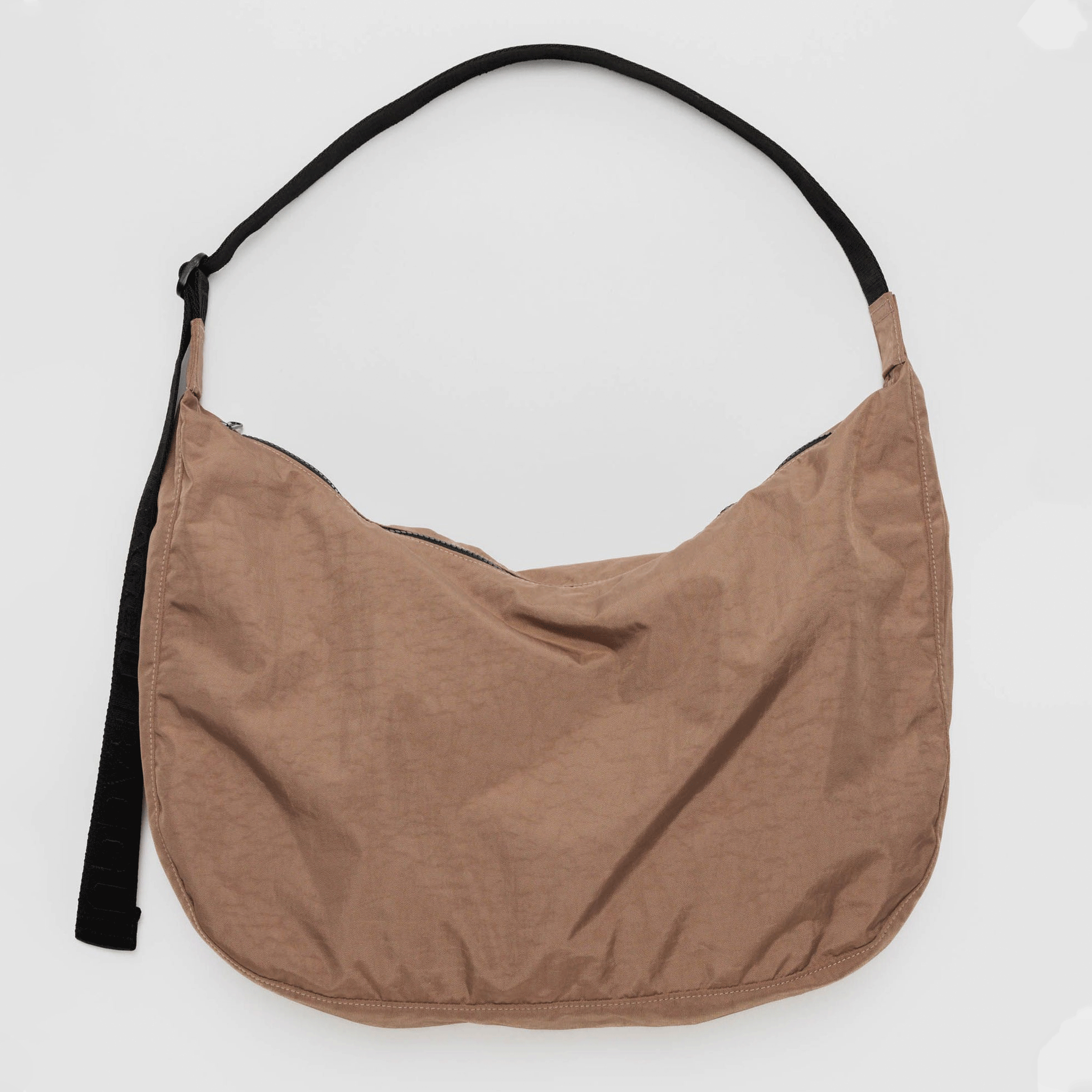 On a white background is a brown nylon crescent shaped tote bag with a black strap and zipper. 