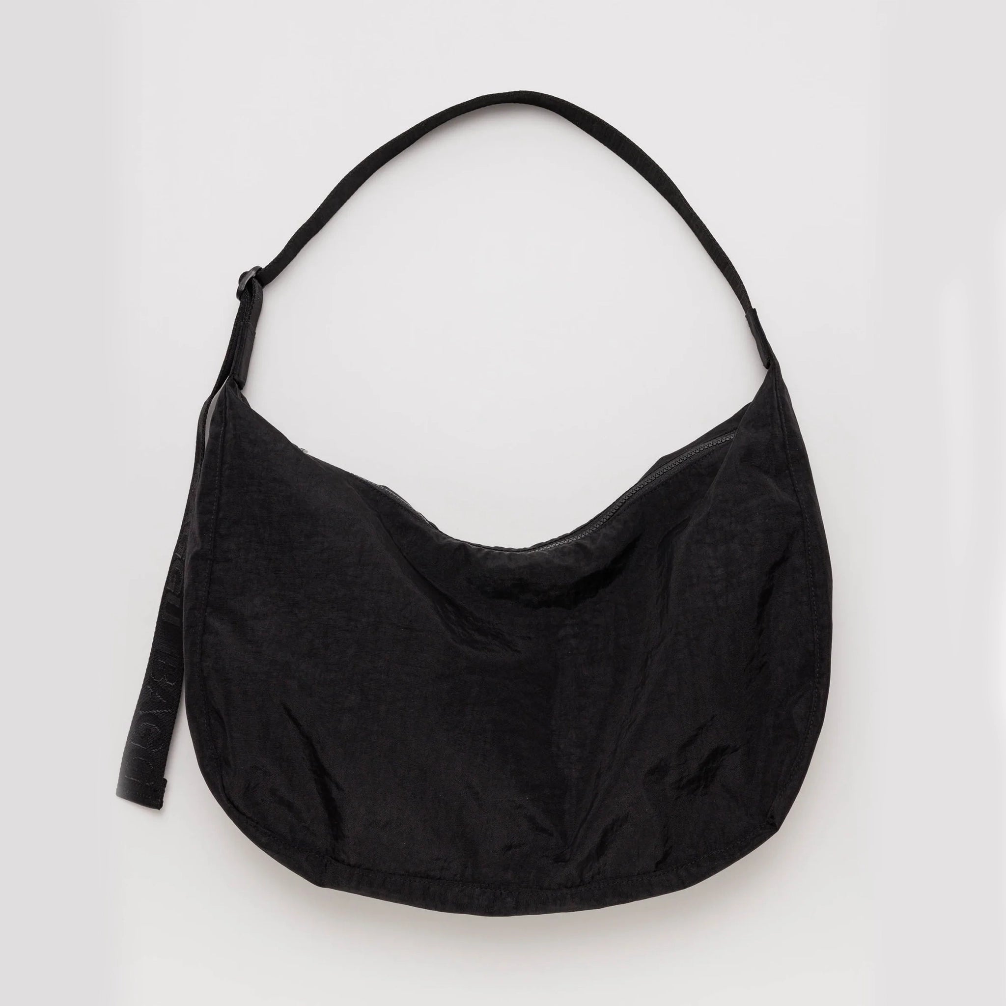 On a white background is a black nylon bag with a black adjustable strap. 