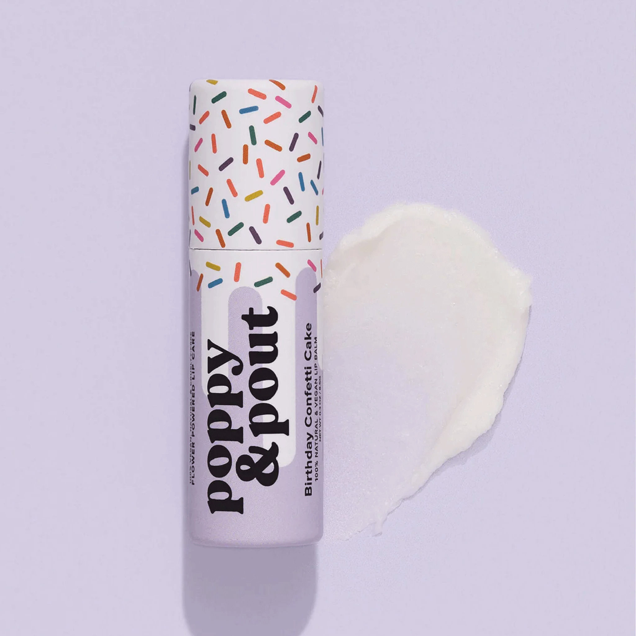 On a lavender background is a purple lip balm with a white and multi color &quot;sprinkle&quot; design with black text that reads, &quot;poopy &amp; pout birthday confetti cake&quot;.