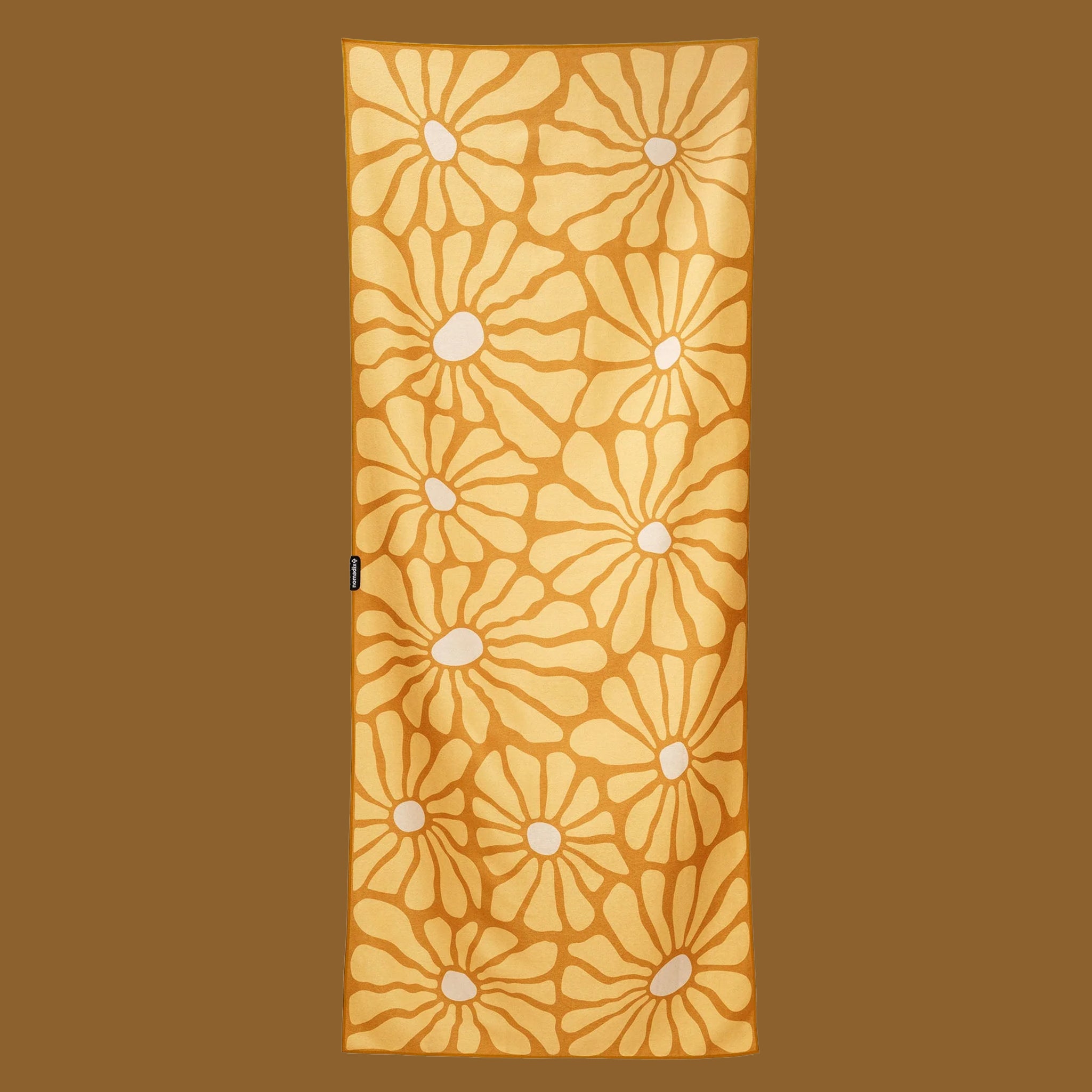 A yellow floral print towel on a brown background.