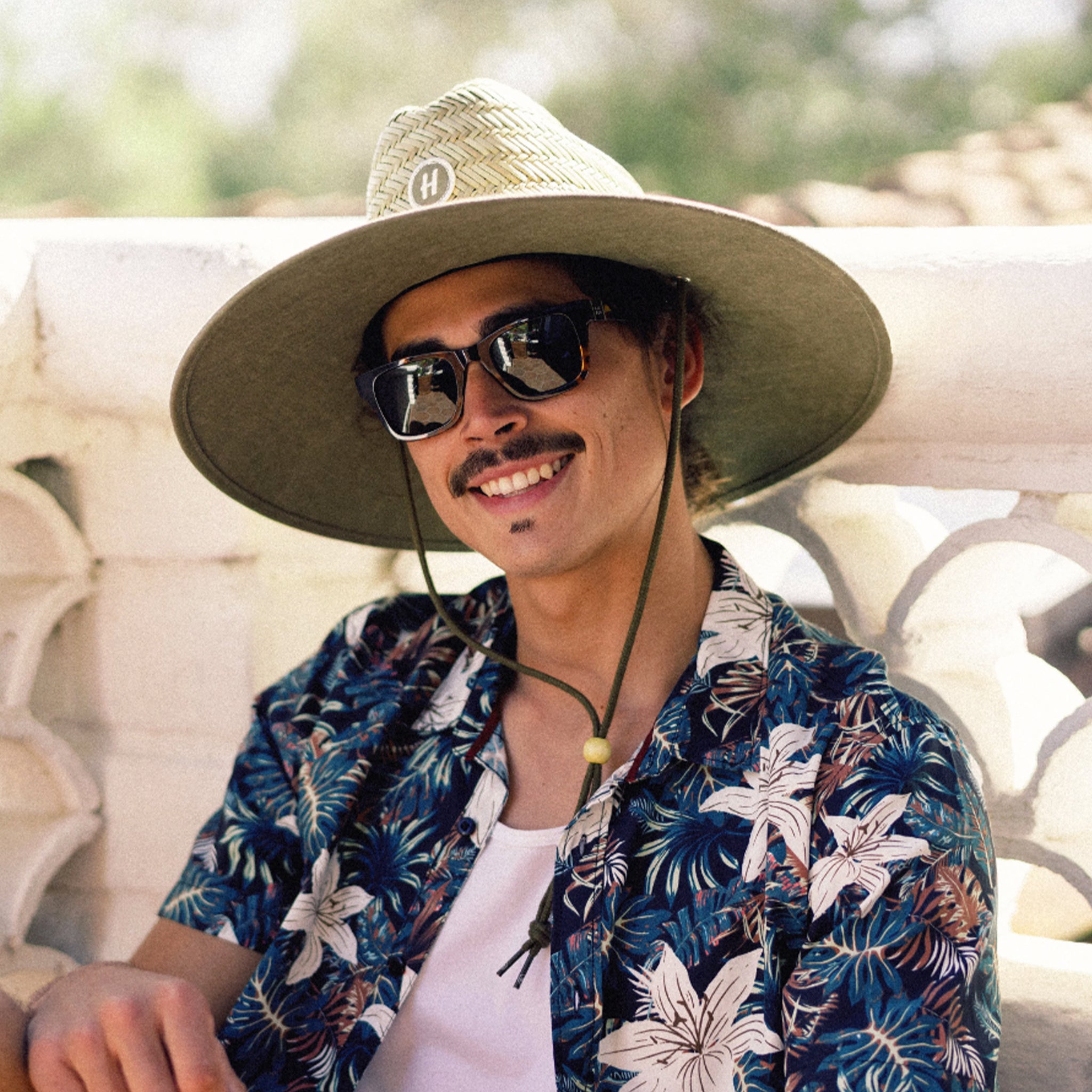 A straw hat with a solid olive green brim. 