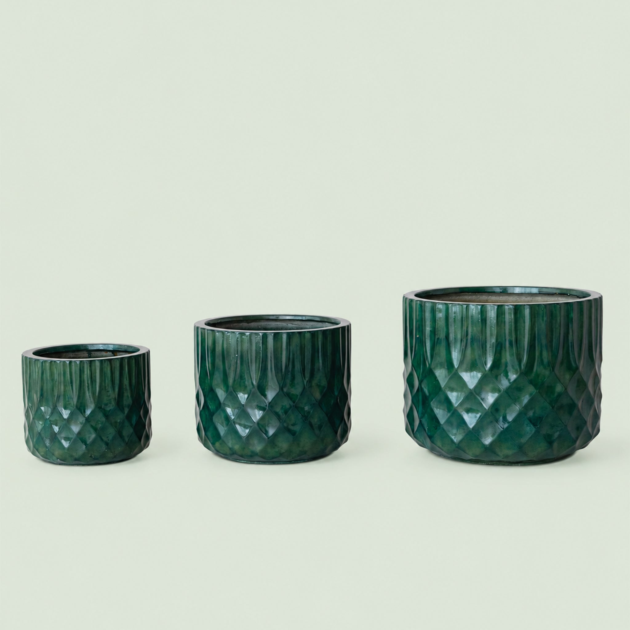 Three green textured planters of different sizes on a light beige background