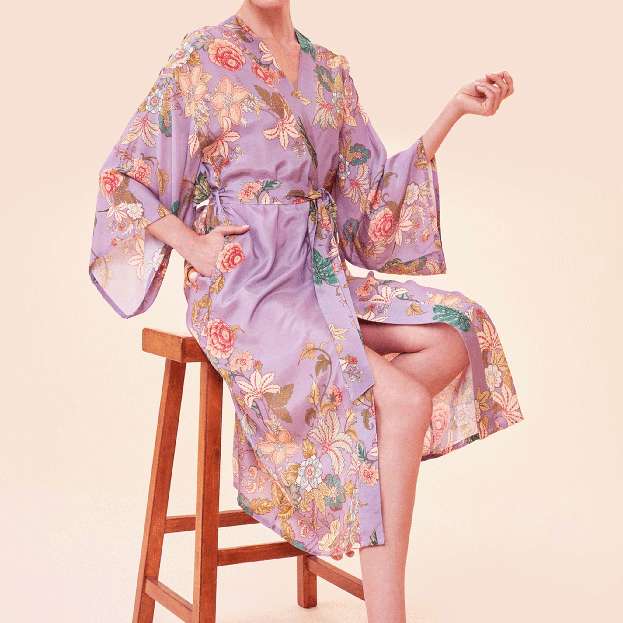 A woman sitting on a stool modelinga lilac robe with a floral and tiger design.