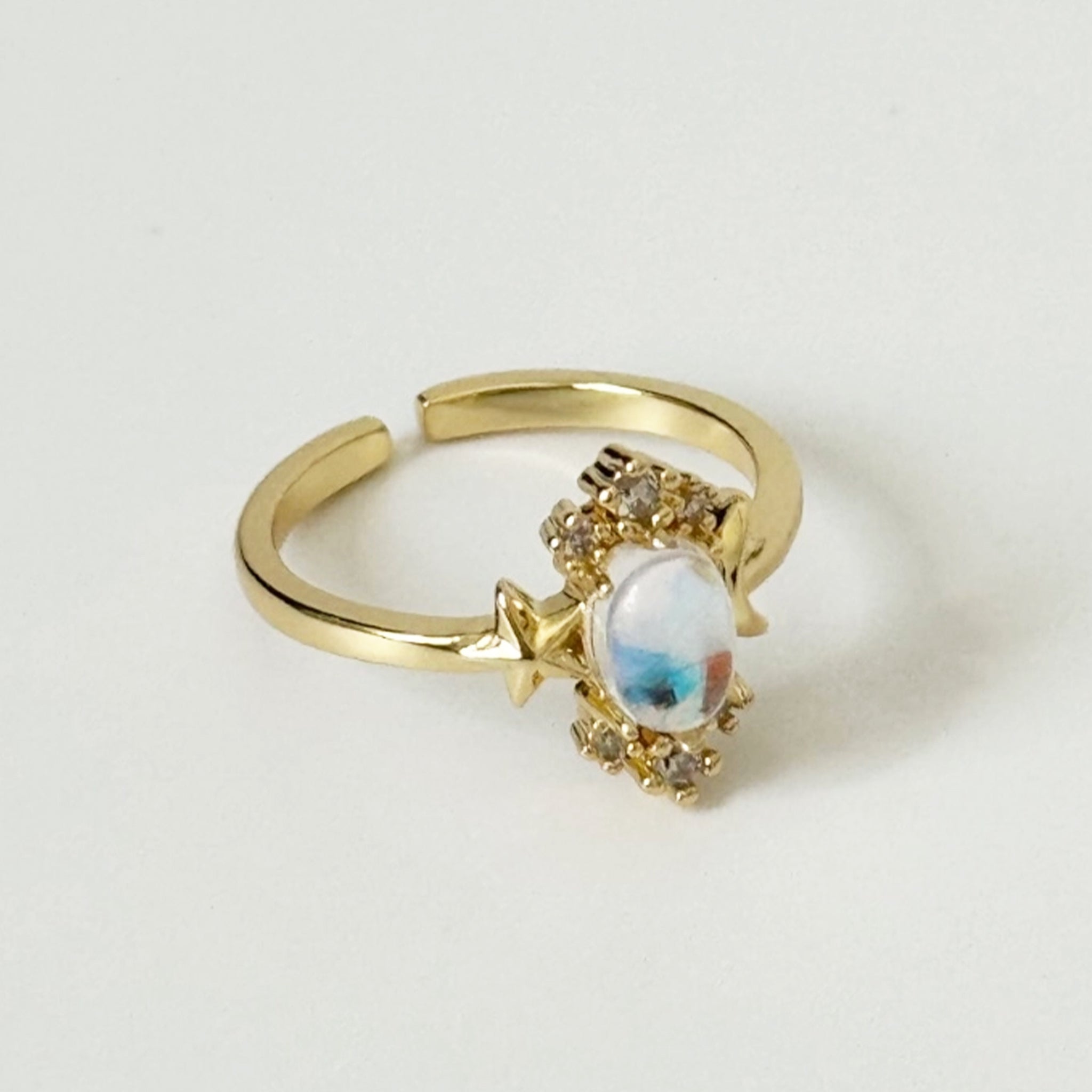 A gold ring with star details and a opal stone in the center. 