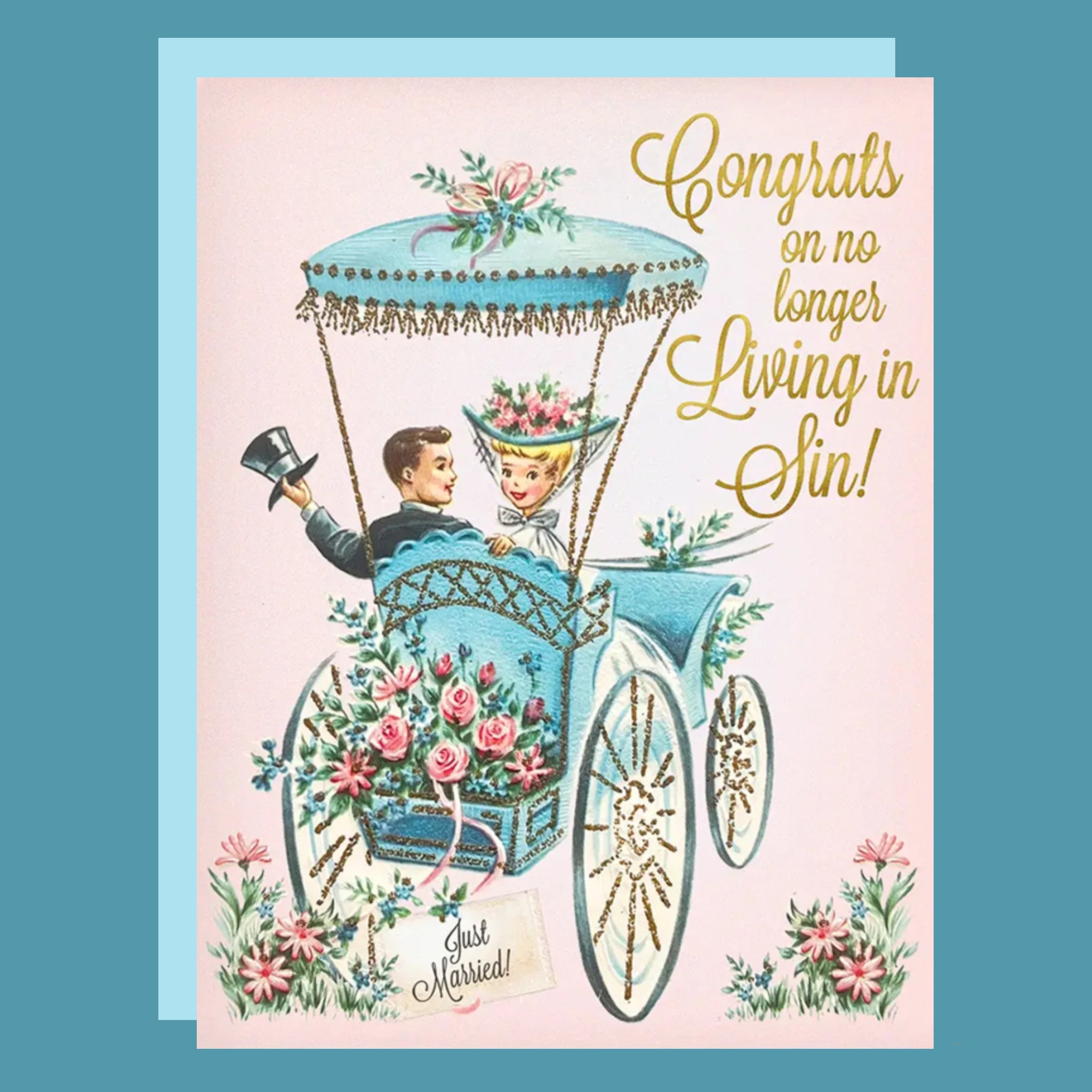 A pink card with a vintage carriage illustration with a newlywed couple paired with a blue envelope and gold foiled text that reads, &#39;Congrats on no longer living in sin!&#39;. 