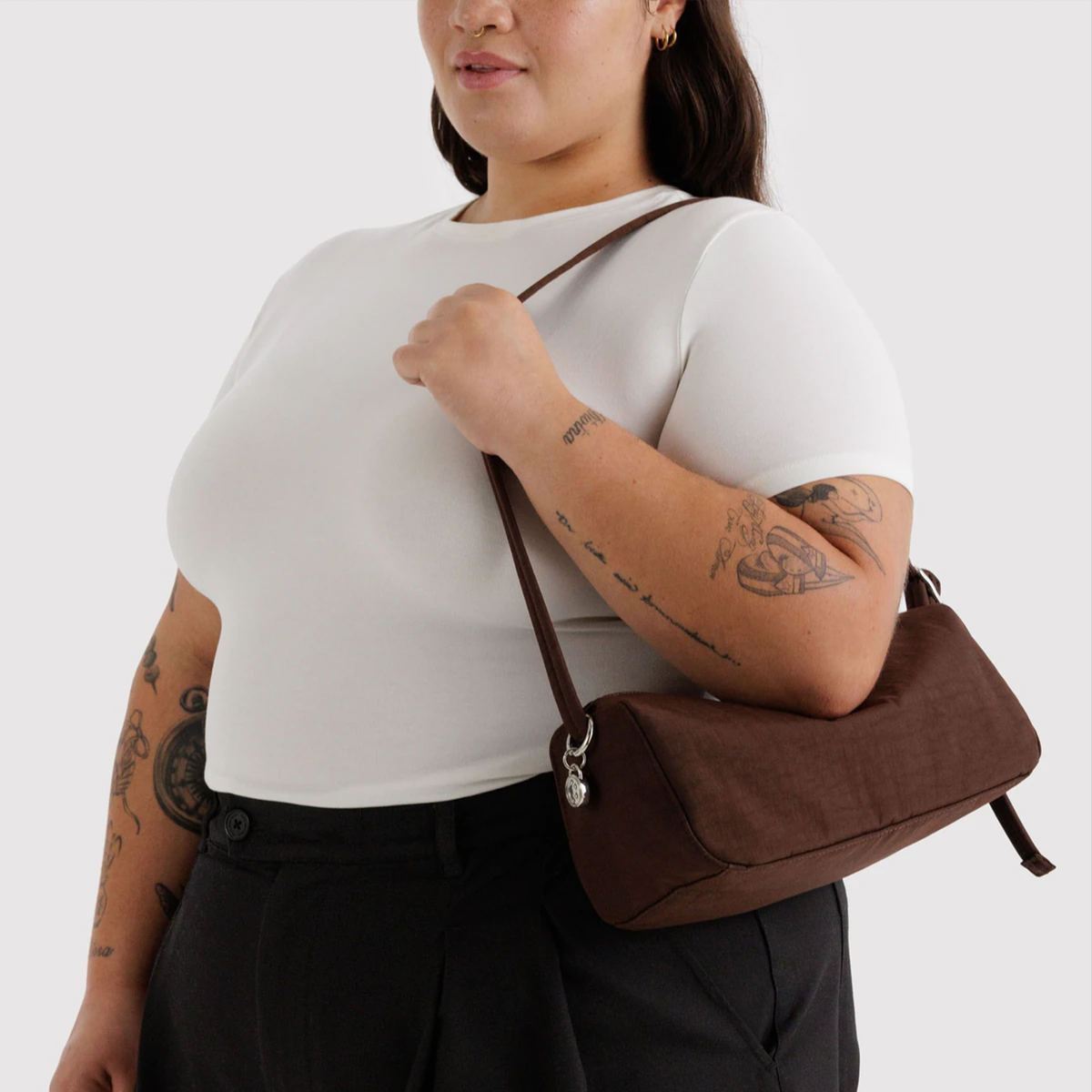 A brown nylon shoulder bag on a model's shoulder.