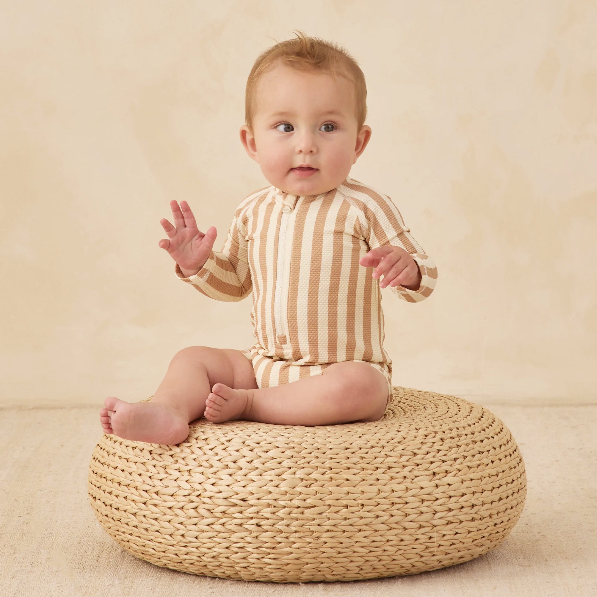 A cream and tan striped rashguard swimsuit for kids. 