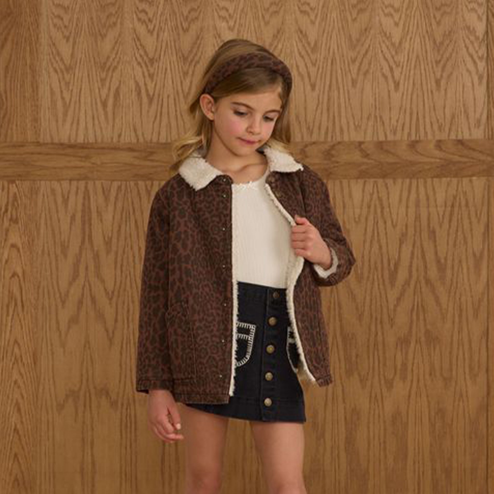 A children's brown leopard print jacket with a cream colored boucle interior and collar. 