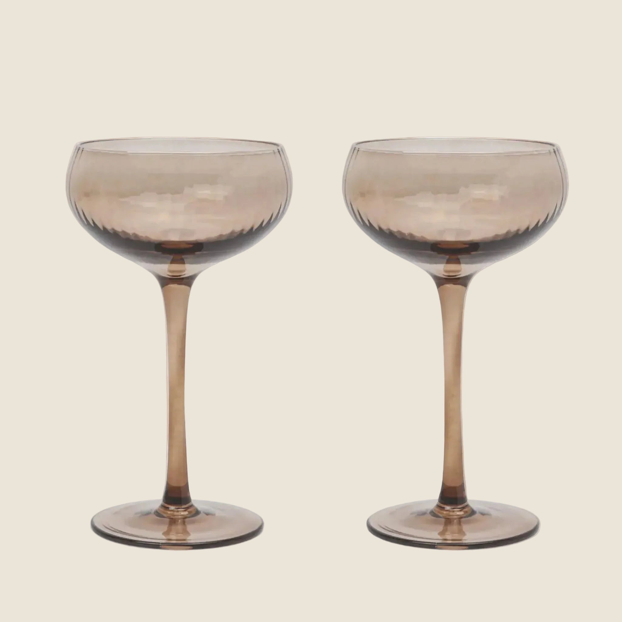 A set of glass coupe glasses in a smokey grey color. 