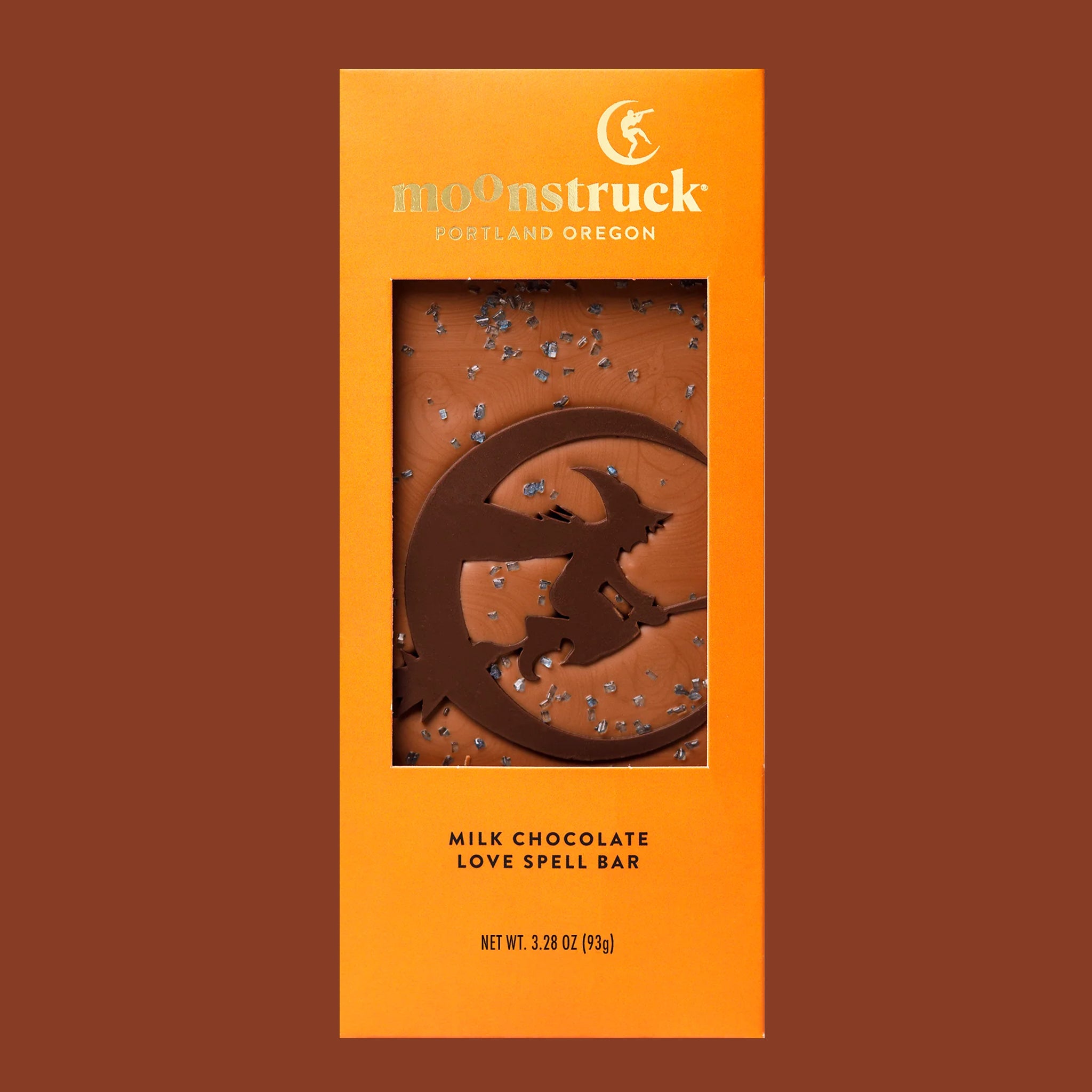An orange packaged bar of chocolate with a moon and witch shaped design in the center. 