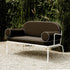 An off white metal frame loveseat outdoor furniture piece with a black cushion.