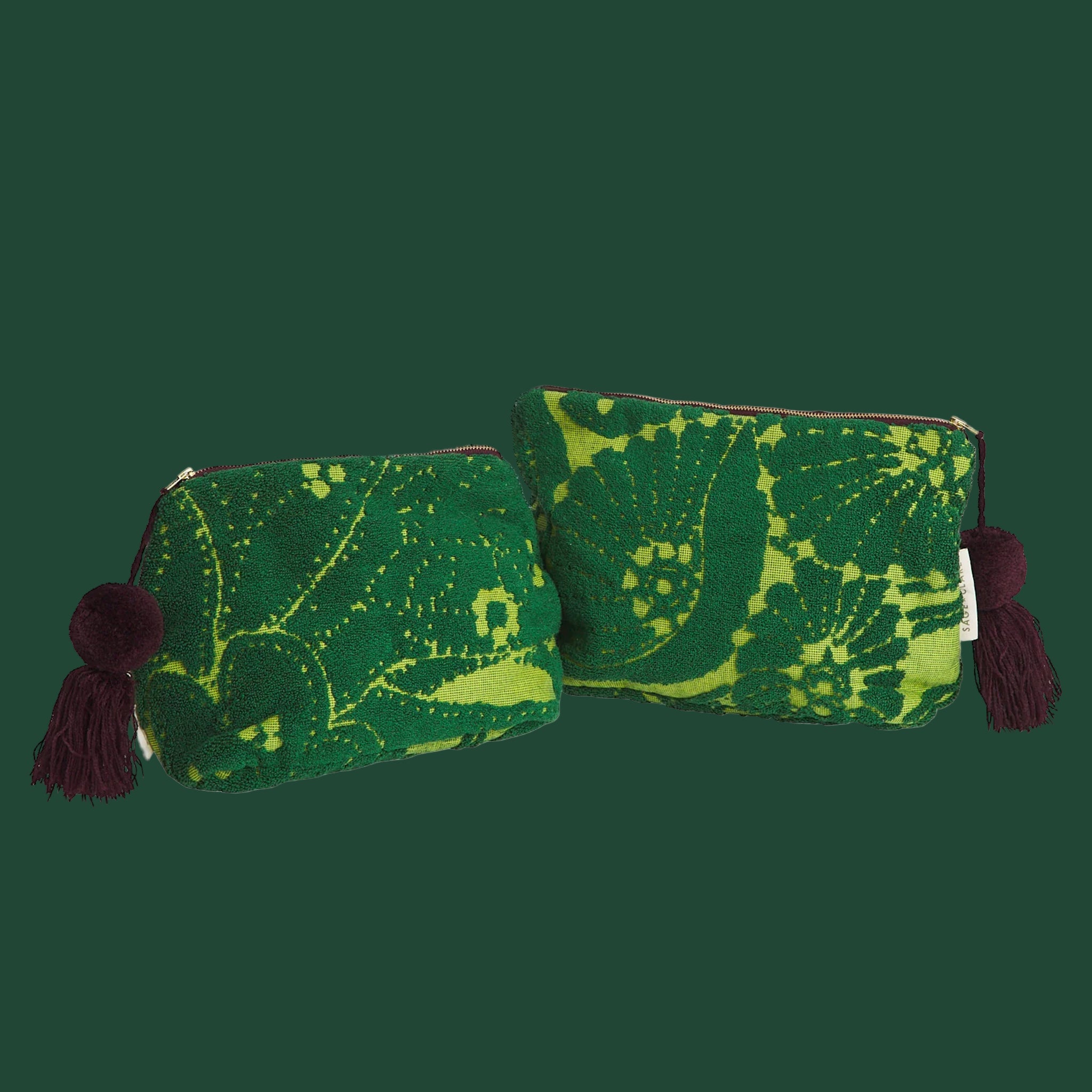 Two different sized green, printed pouches with a brown tassel on the zippers. 