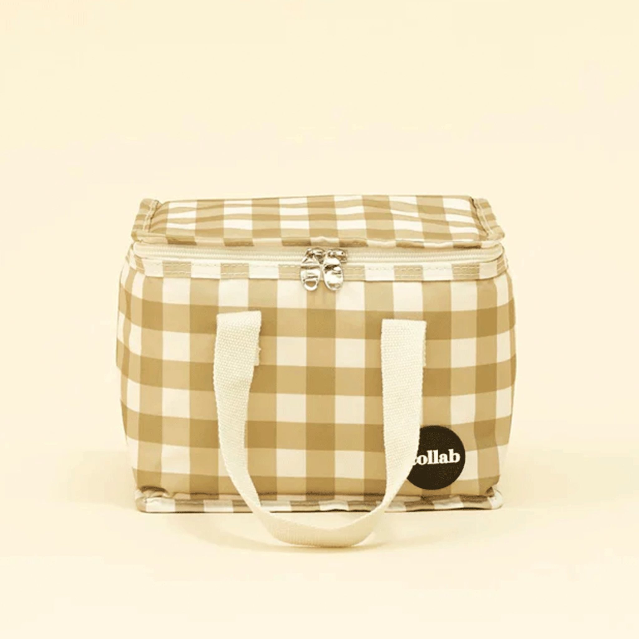 On a light yellow background is an ivory and green checkered lunch box.