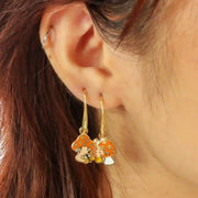  A model wearing the gold and orange mushroom shaped earrings with small daisies.