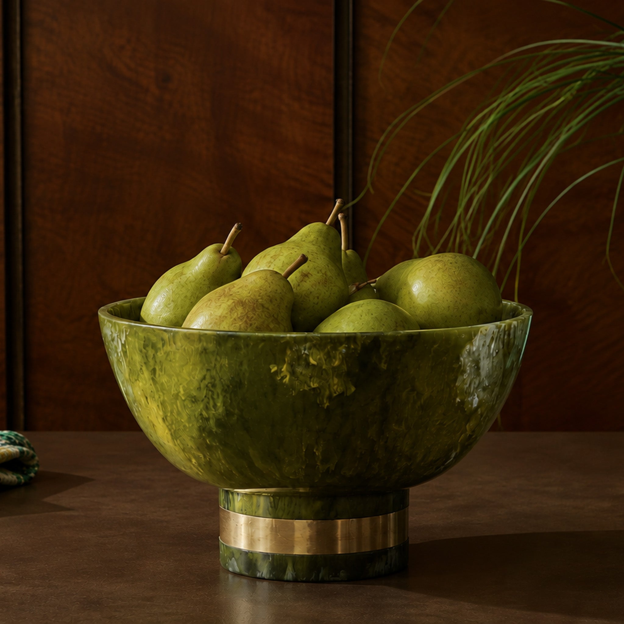 A green bowl with a gold detail and pears inside of it in a wood kitchen.