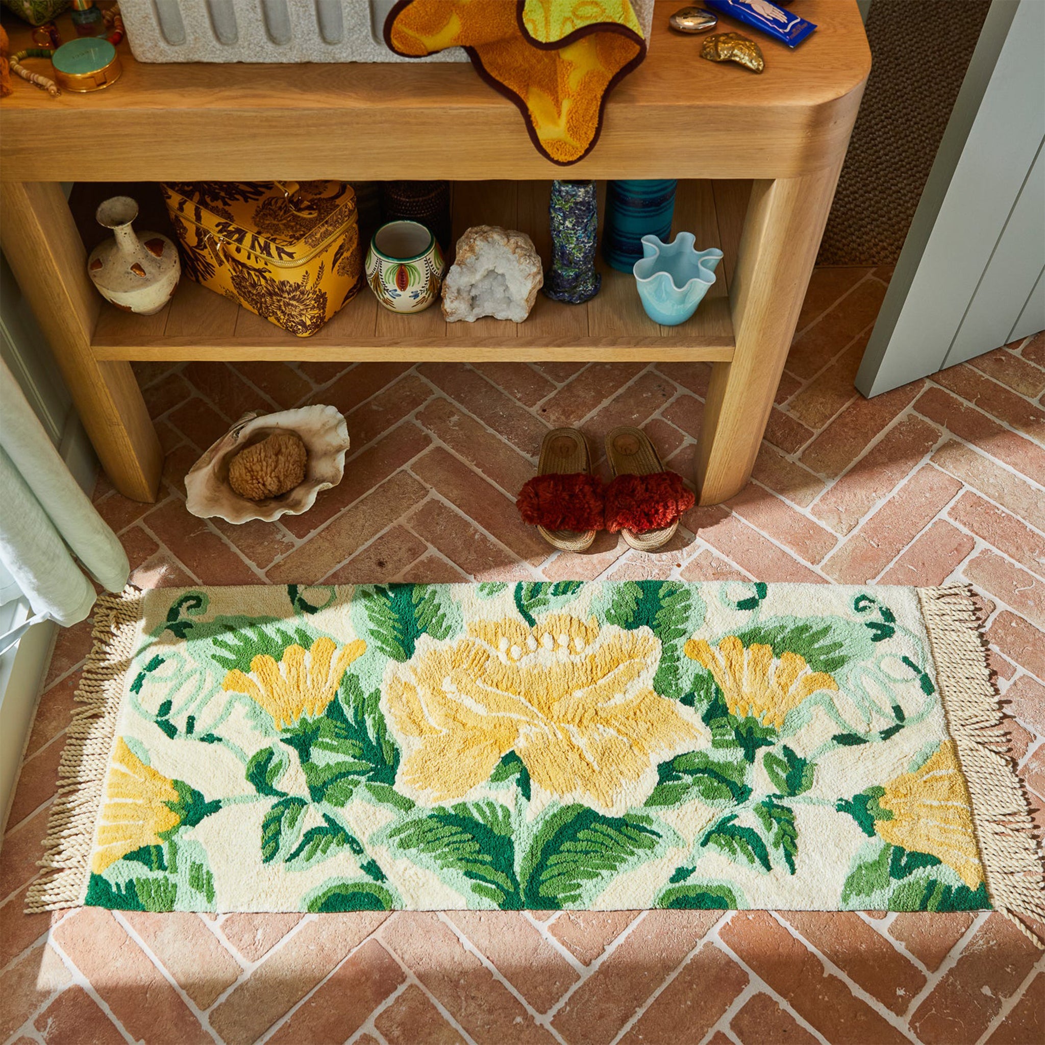 A green and yellow floral bath runner with fringe on each end. 