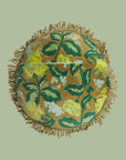A green round floral print pillow with olive green tassels around the entire pillow. 