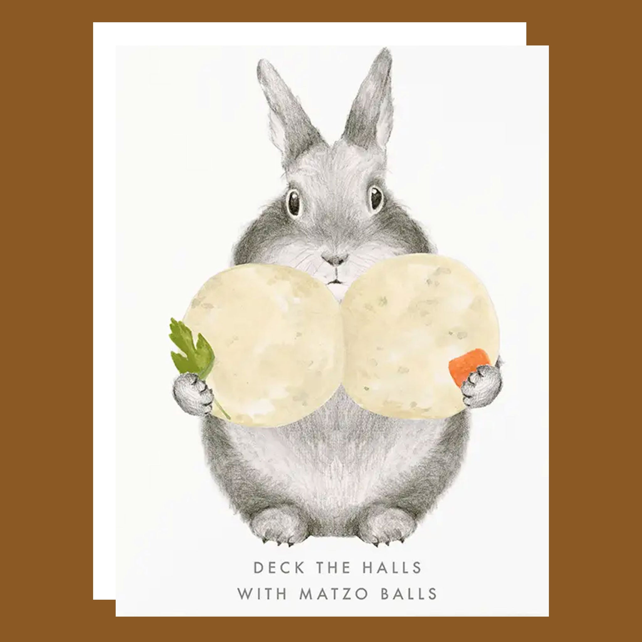 A white card with an illustration of a bunny holding matzo balls with text that reads, 'Deck The Halls With Matzo Balls'. 