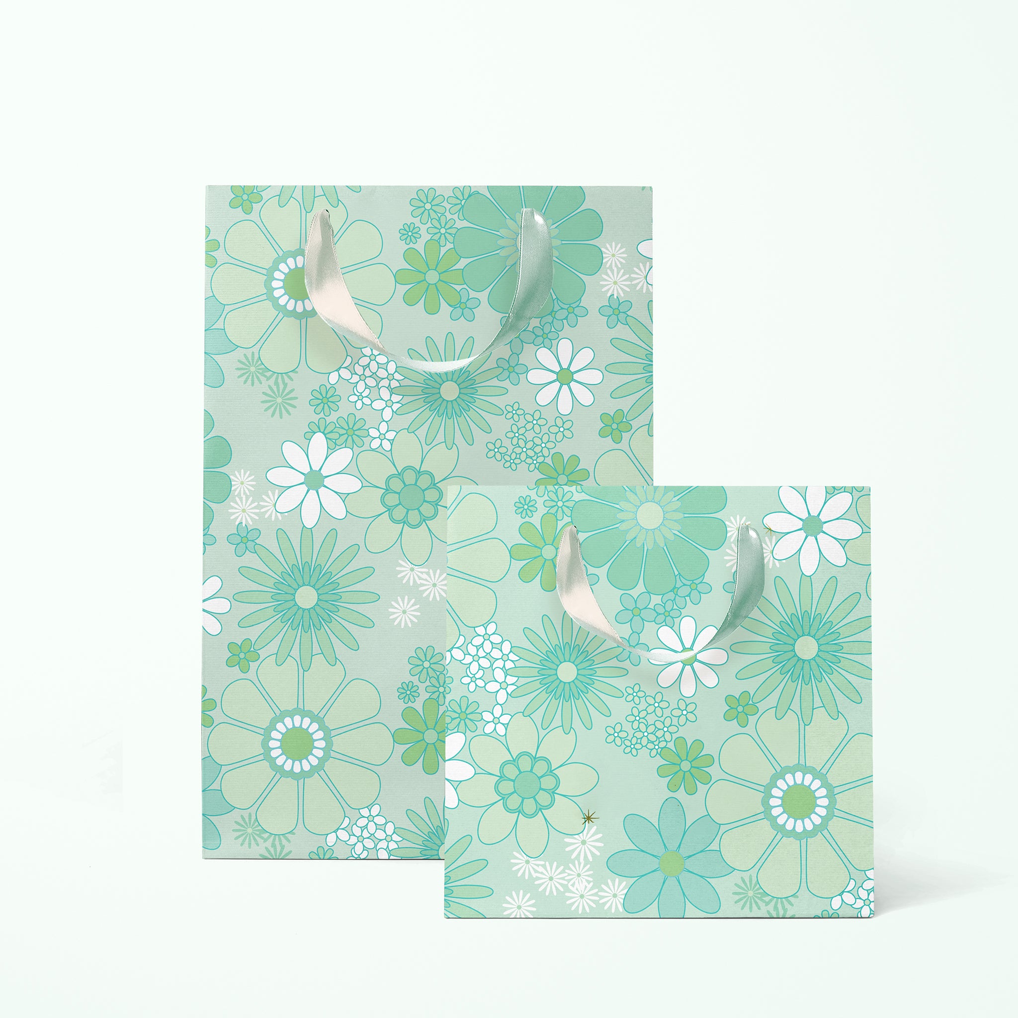On a white background is a rendering of two gift bags with a mint and white floral print and ribbon handles. 