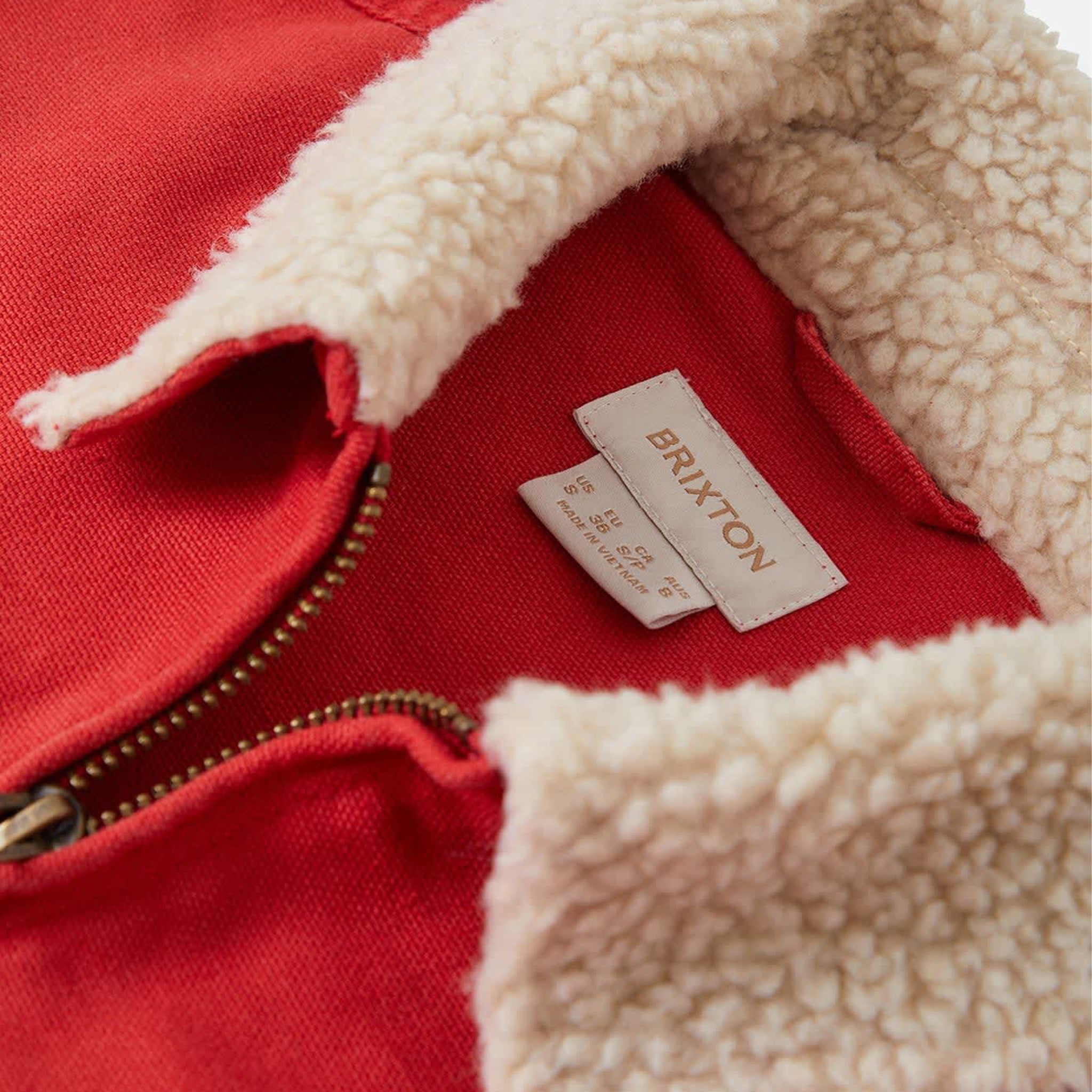 Red zip up jacket with tan fur collar trim. 