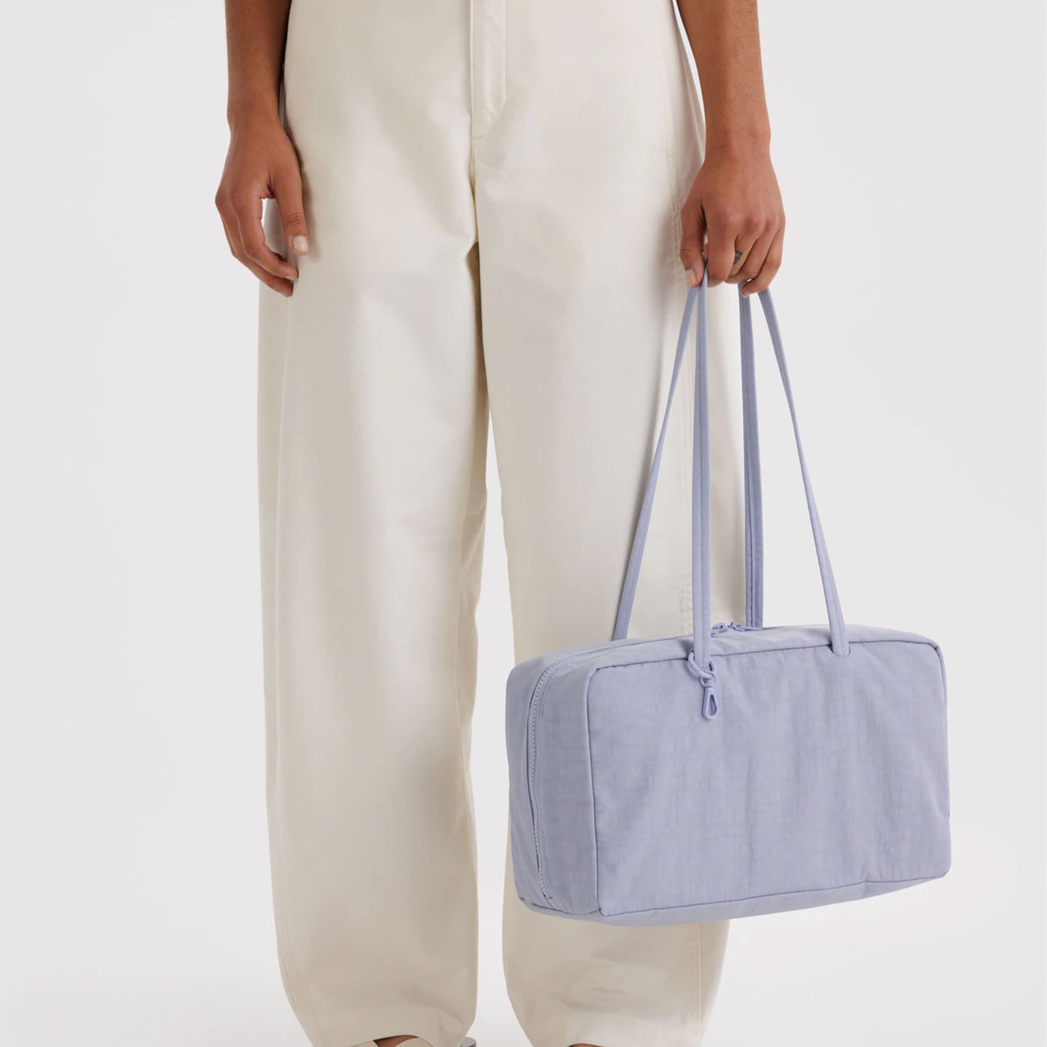 A light blueish-purple nylon rectangle shaped shoulder bag. 