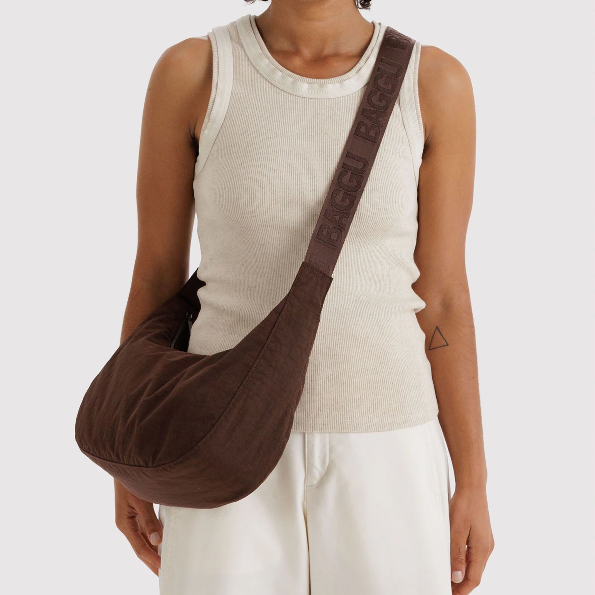 A dark brown crescent shaped bag with a shoulder strap and an adjustable crossbody. 