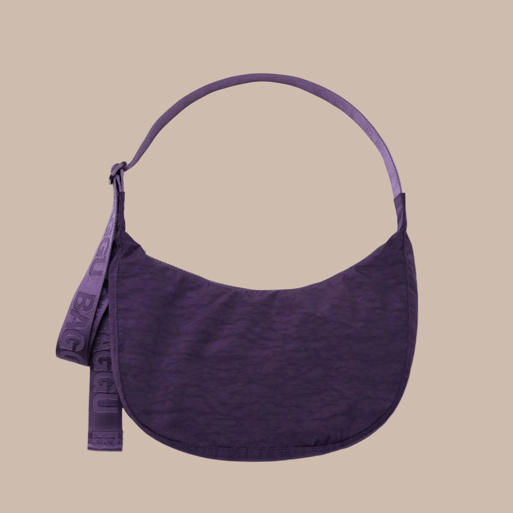 A dark purple crescent shaped nylon shoulder bag that can also be extended to a crossbody. 