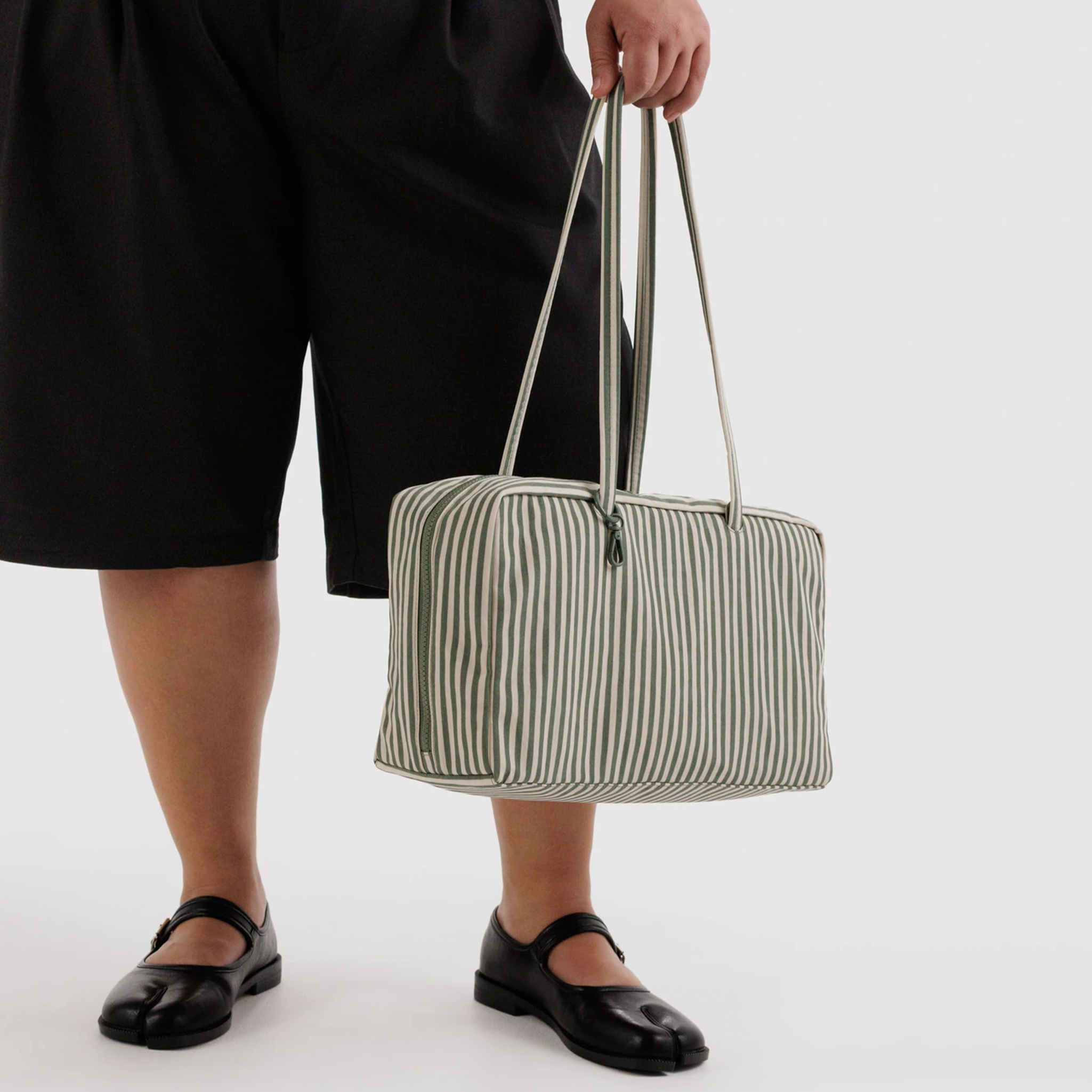 sage striped nylon bag in a model's hands.