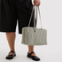 sage striped nylon bag in a model's hands.