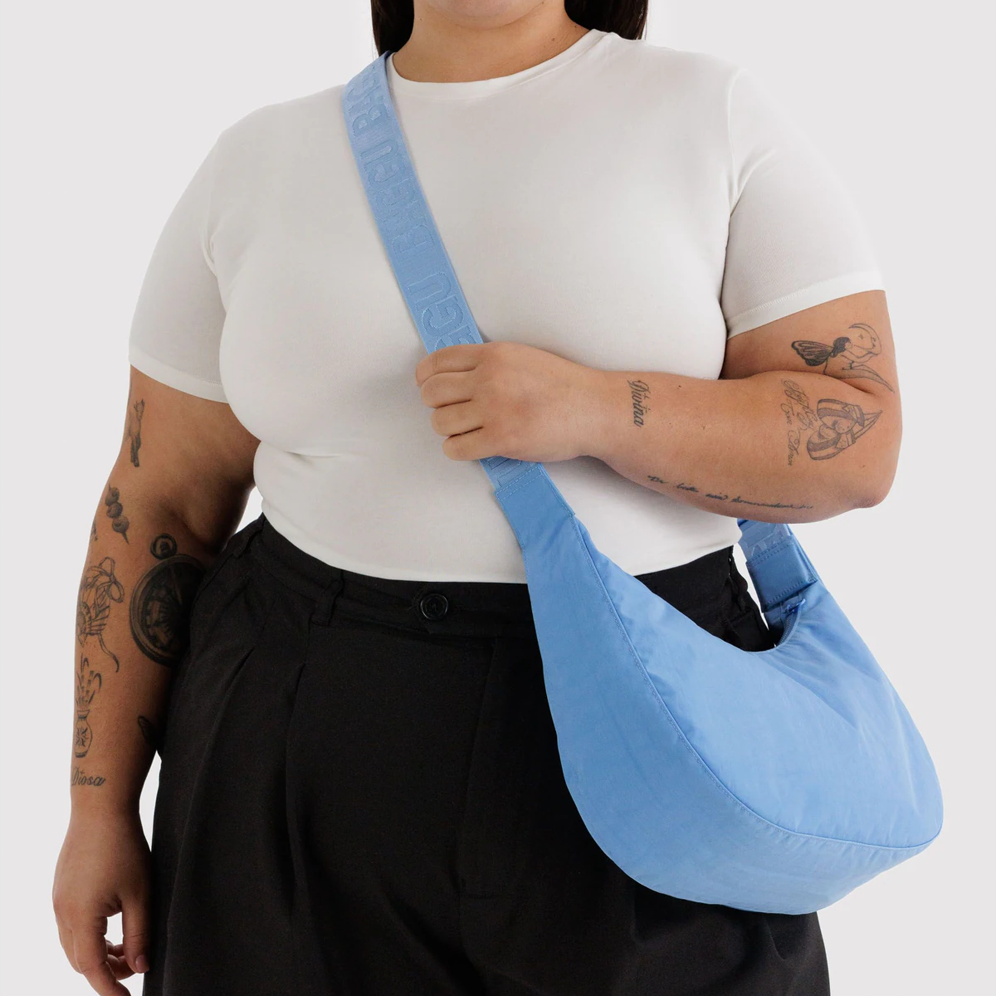 A blue nylon crossbody bag on a model.