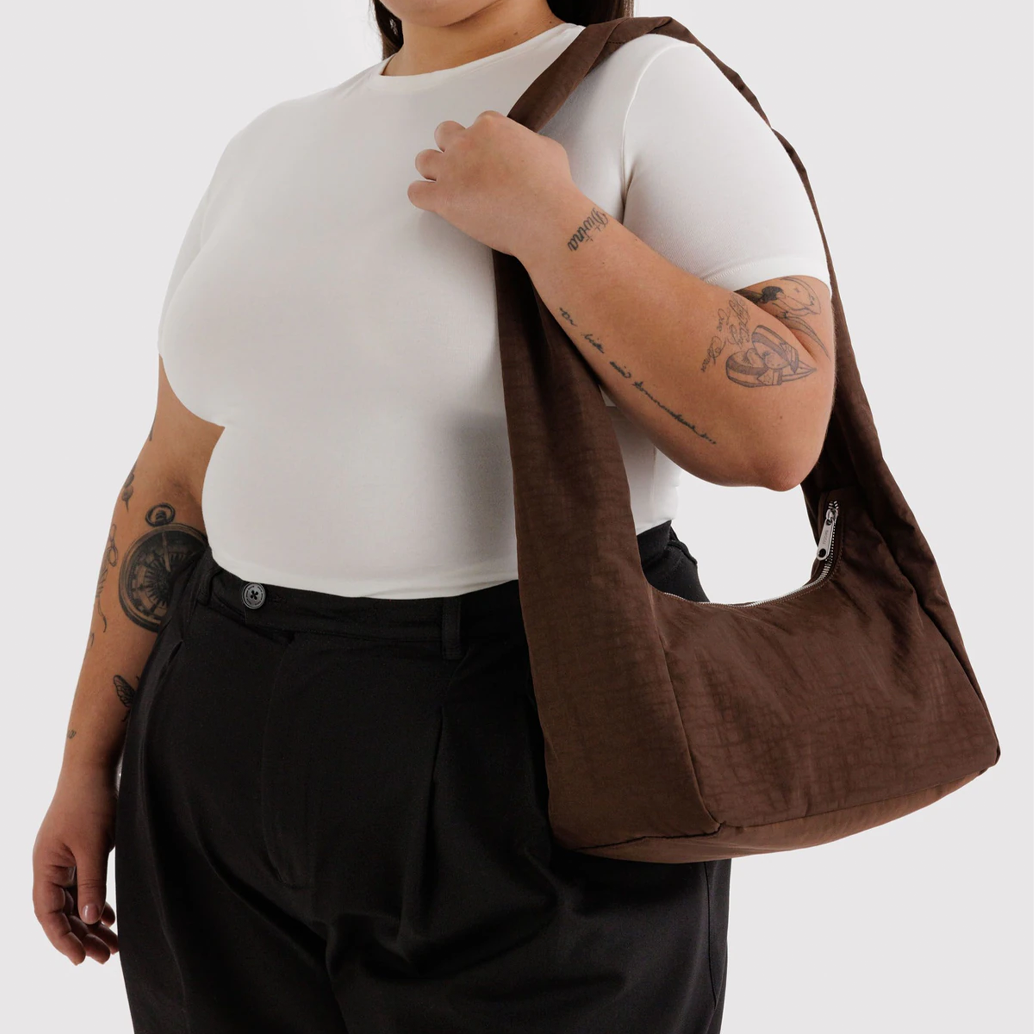 A brown nylon shoulder bag with long shoulder straps on a model's shoulder.