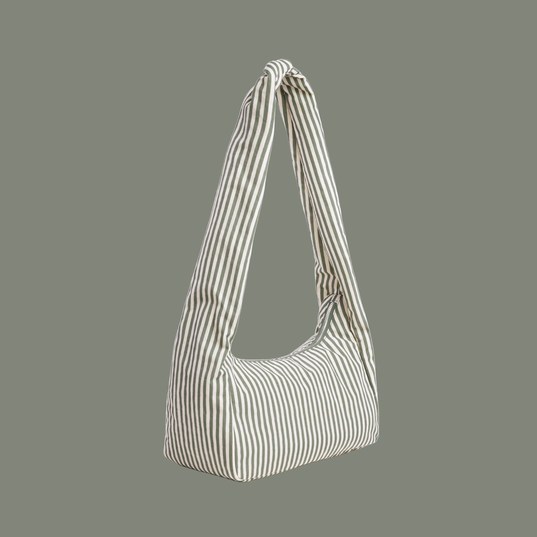 A sage striped nylon shoulder bag with long shoulder strap on a sage colored background.