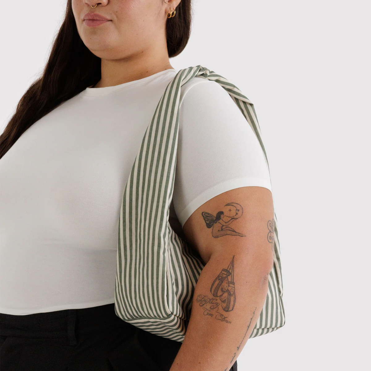 sage striped nylon bag on a model's shoulder.