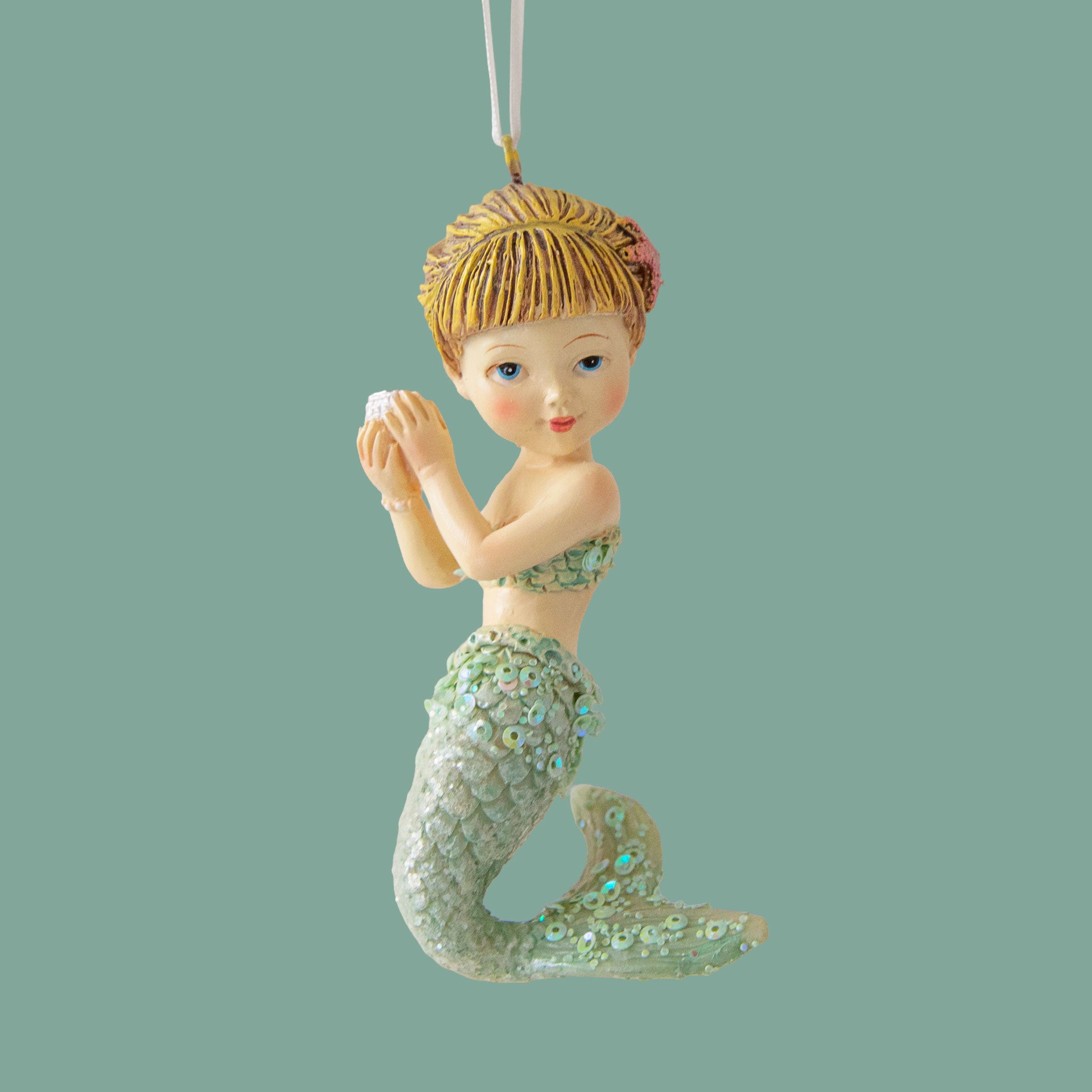 A mermaid shaped ornament holding a pearl. 