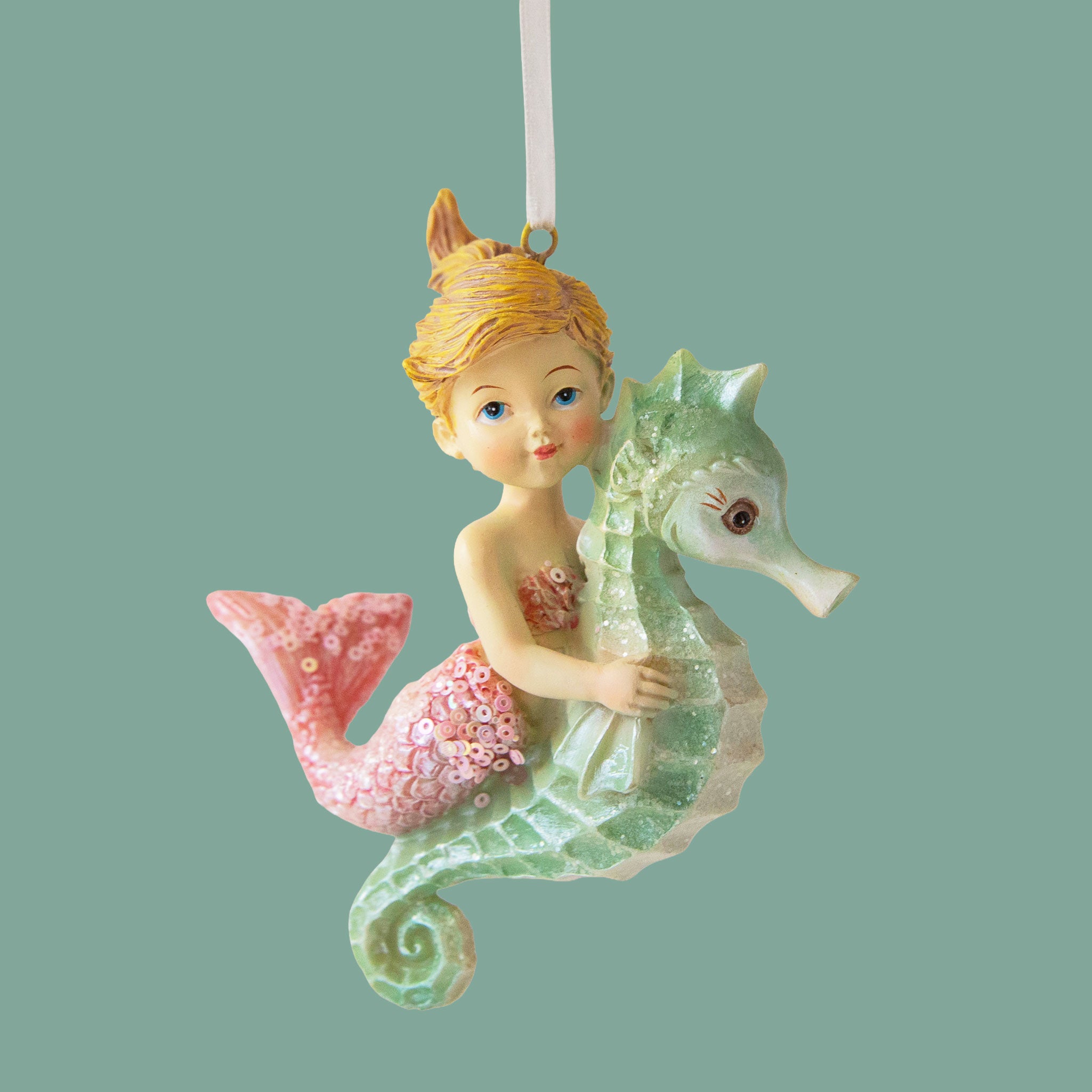 A mermaid shaped ornament with a pink tail.  The mermaid is riding a mint colored seahorse.