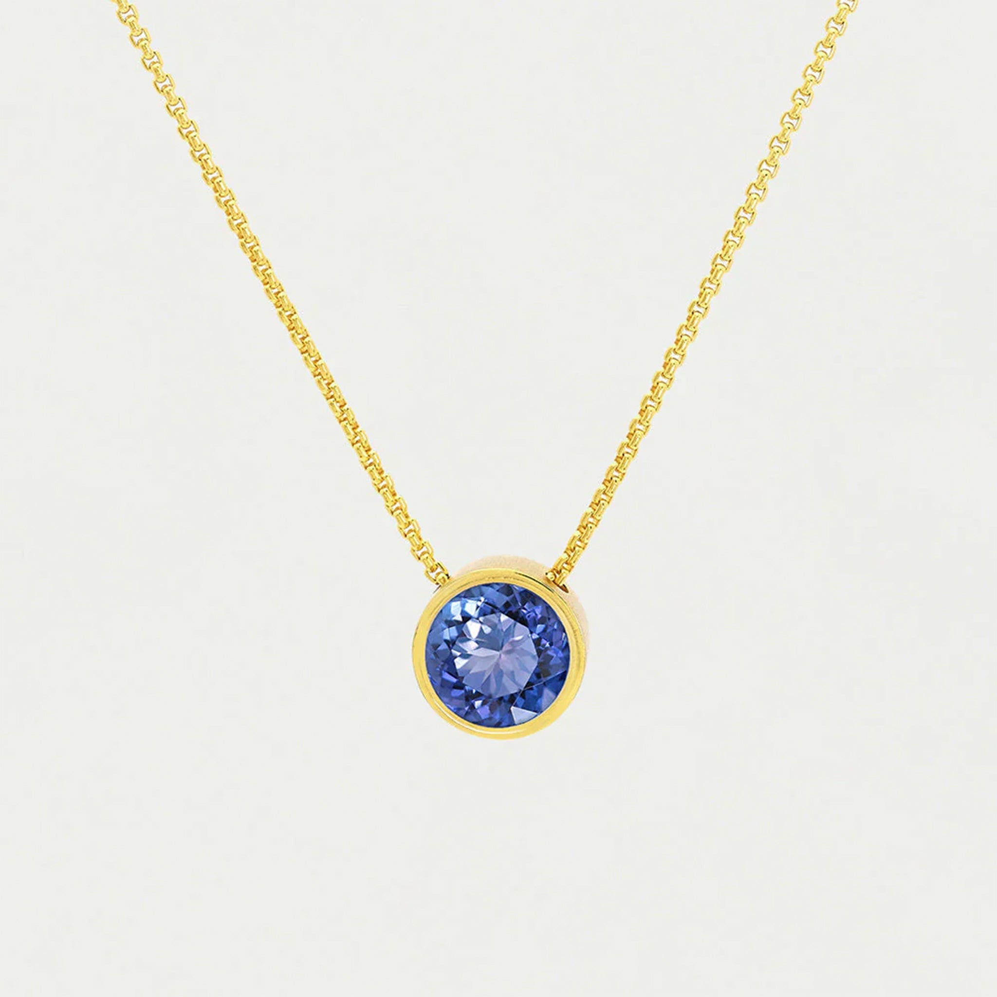 A gold chain necklace with a round midnight blue cz stone in the center. 