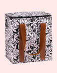 A black and white lunch box with brown leather handles. 