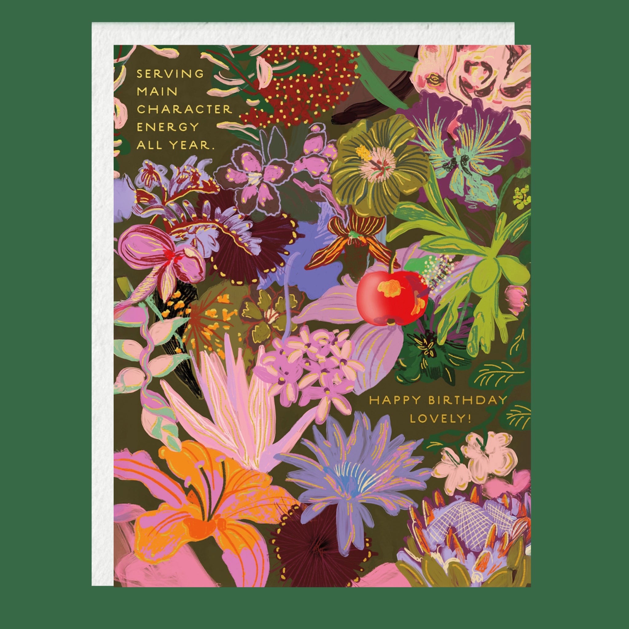 A square floral greeting card with a white envelope behind it, featuring a dense botanical illustration in pink, purple, green, orange, and gold text that reads 'SERVING MAIN CHARACTER ENERGY ALL YEAR.' and 'HAPPY BIRTHDAY LOVELY!' on a dark green background.
