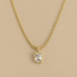 A gold chain necklace with a rectangular bezel-set clear gemstone pendant, displayed against a solid beige background.