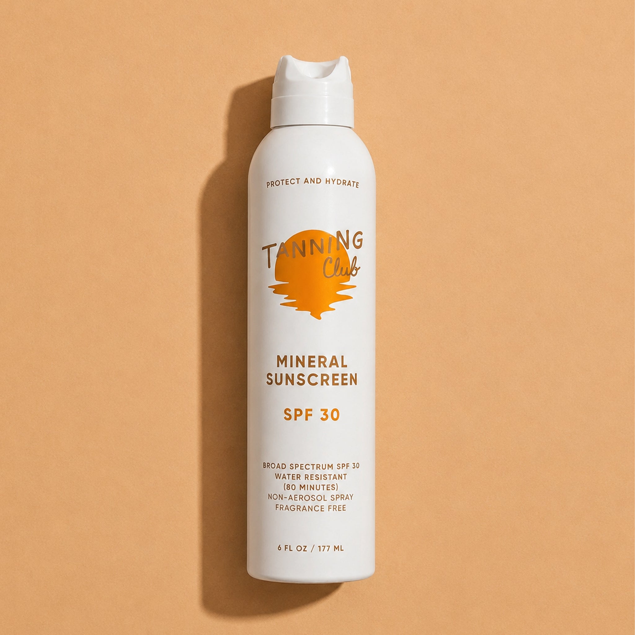 Tanning Club mineral sunscreen spray bottle on a beige background