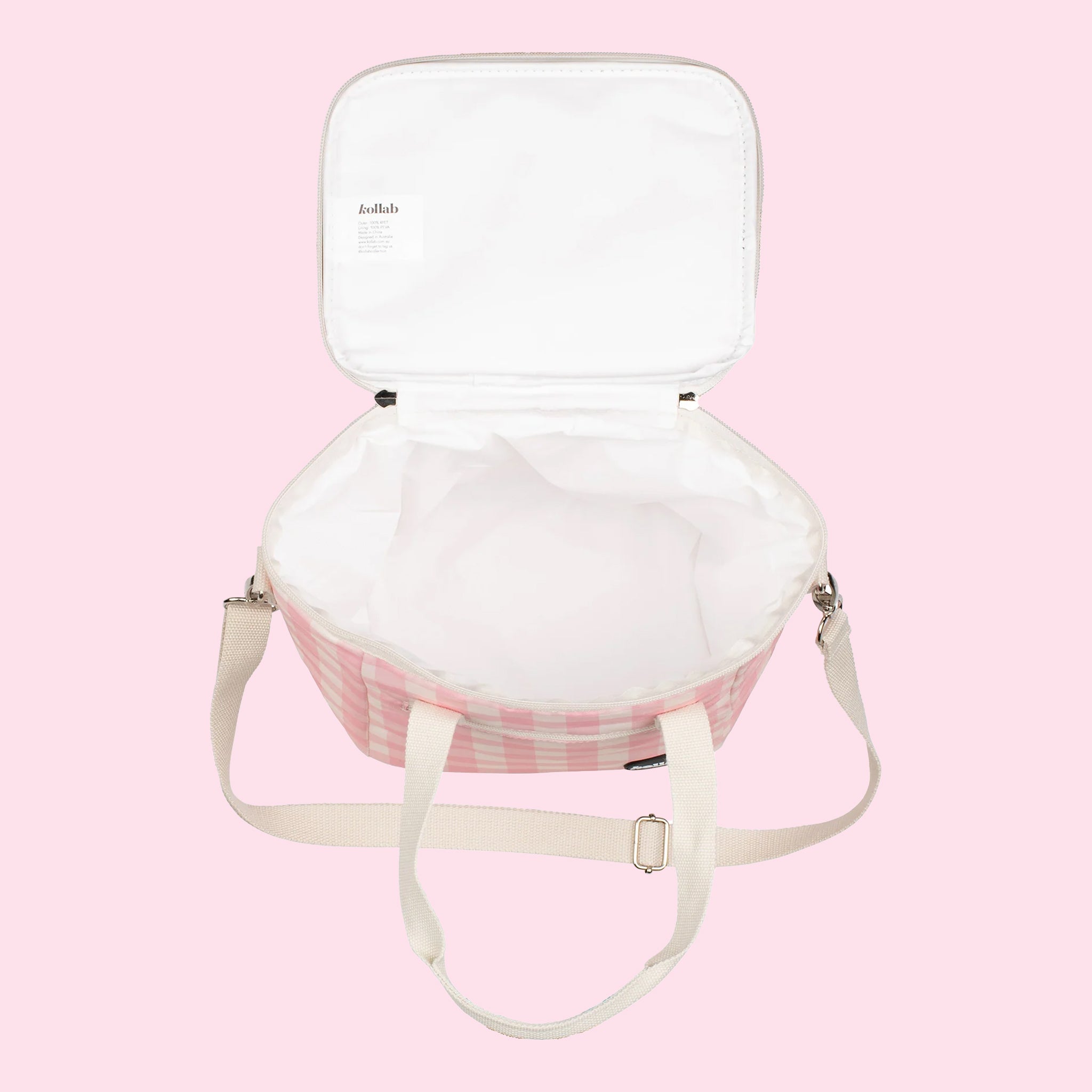 On a light pink background is a pink and white cooler bag with a long adjustable strap.
