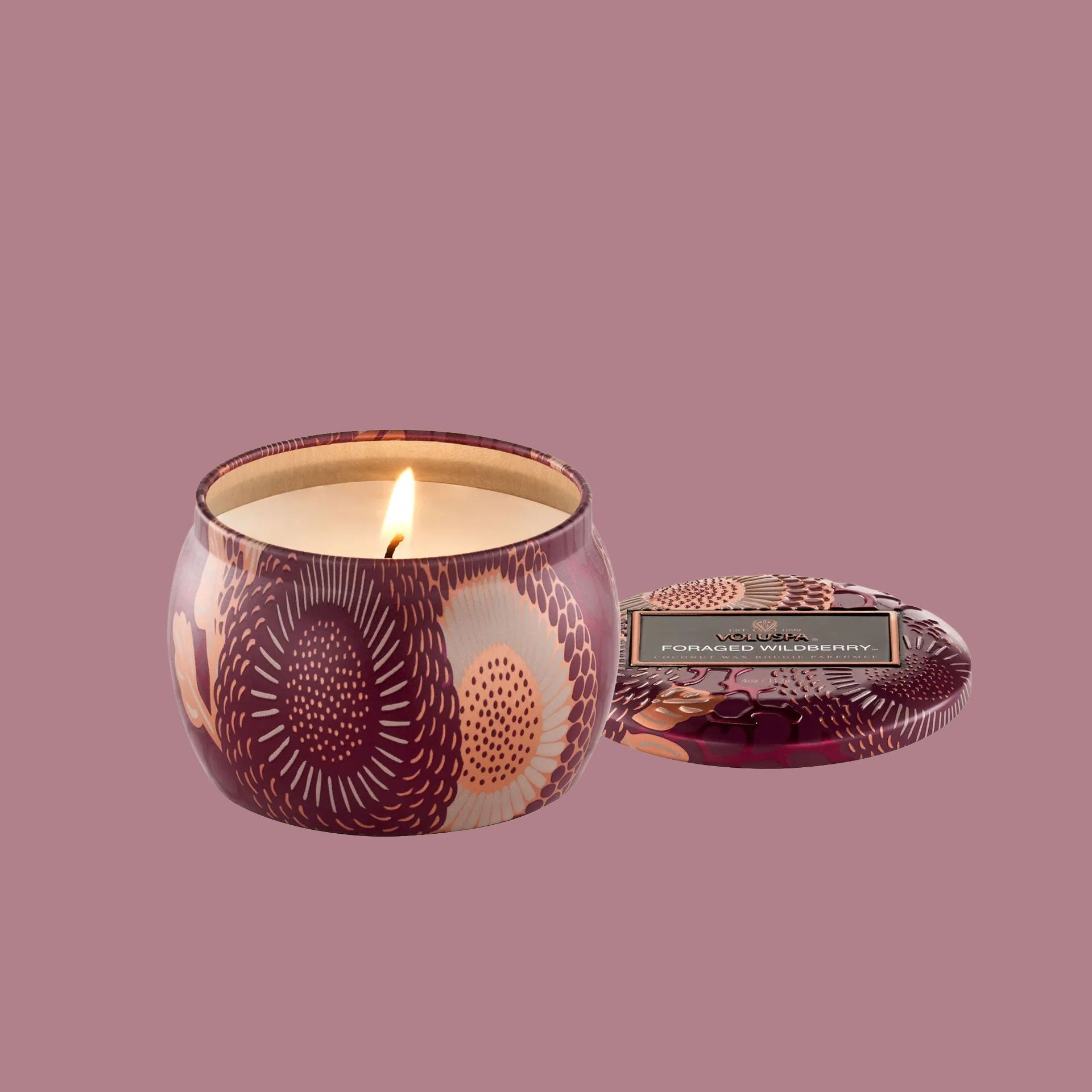 A burgundy metal tin candle with a lid. 
