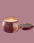 A burgundy metal tin candle with a lid. 