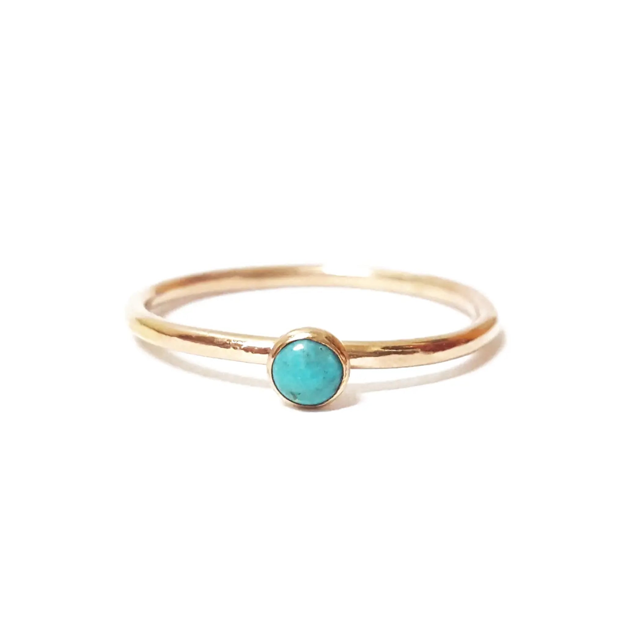 A gold thin band ring with a single mini turquoise stone in the center. 